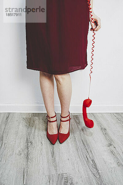 Frau hält roten Telefonhörer