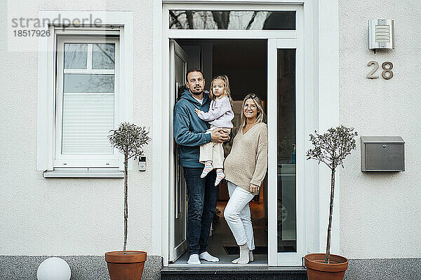 Glückliche Familie steht vor der Haustür