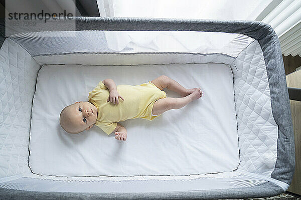 Cute baby boy lying in crib
