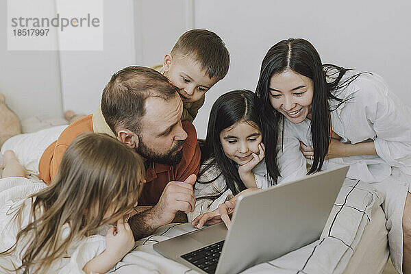 Glückliche Familie benutzt Laptop im Schlafzimmer zu Hause