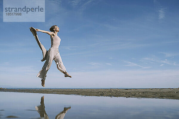 Sorglose Frau springt am Strand