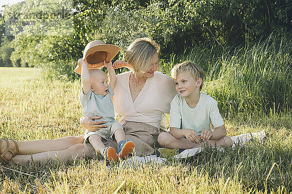 Glückliche Mutter sitzt mit Söhnen in der Natur