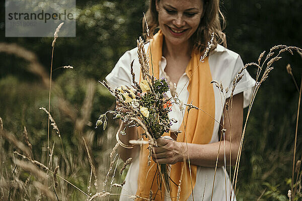 Glückliche Frau mit einem Strauß Wildblumen im Feld