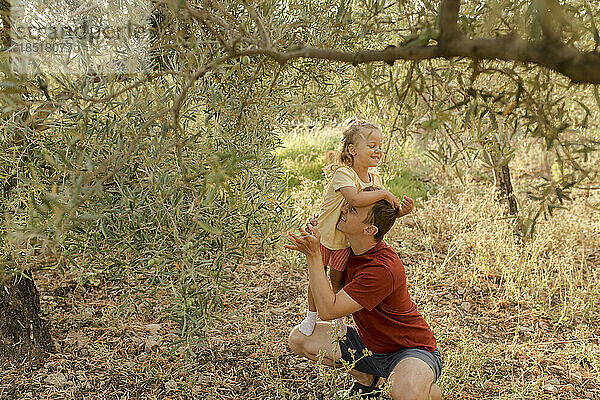 Glücklicher Vater und Tochter  die gemeinsam Spaß im Olivengarten haben