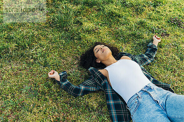 Junge Frau mit geschlossenen Augen entspannt sich im Gras