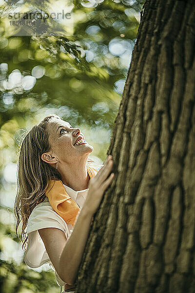 Glückliche Frau am Baum im Wald
