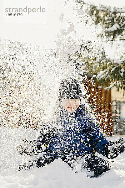 Boy wearing knit hat playing in snow