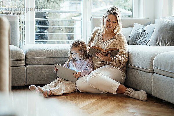 Mutter liest Buch von Tochter mit Tablet-PC zu Hause