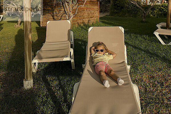 Cute girl wearing sunglasses lying on lounge chair