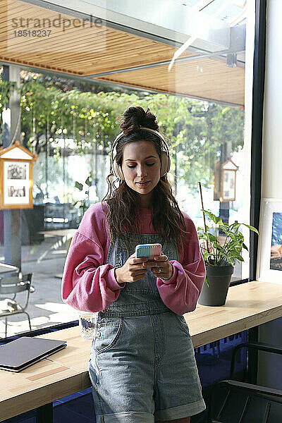 Junger Freiberufler nutzt Smartphone im Café
