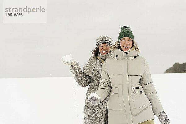 Glückliche Frauen  die im Winter mit Schneeball spazieren gehen