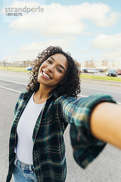 Glückliche junge Frau  die unterwegs ein Selfie macht