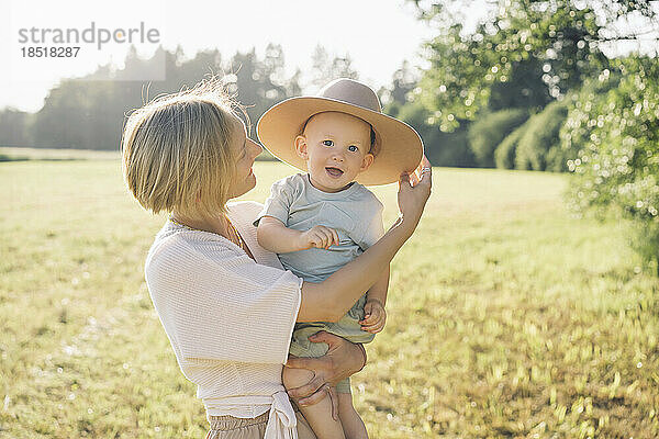 Glückliche Mutter mit Sohn mit Hut in der Natur an einem sonnigen Tag