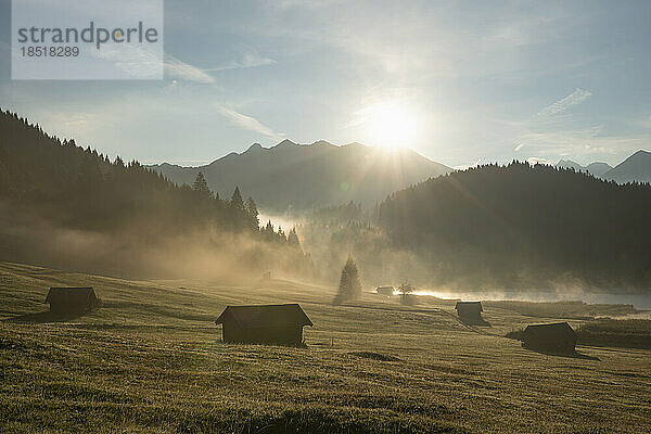 Deutschland  Bayern  abgeschiedene Hütten im Karwendelgebirge bei nebligem Sonnenaufgang mit dem Geroldsee im Hintergrund