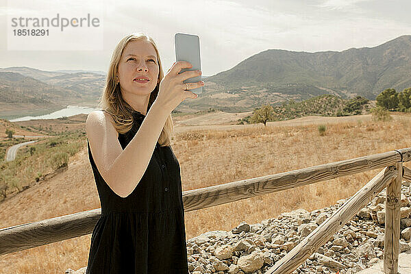 Frau fotografiert an einem sonnigen Tag mit dem Smartphone