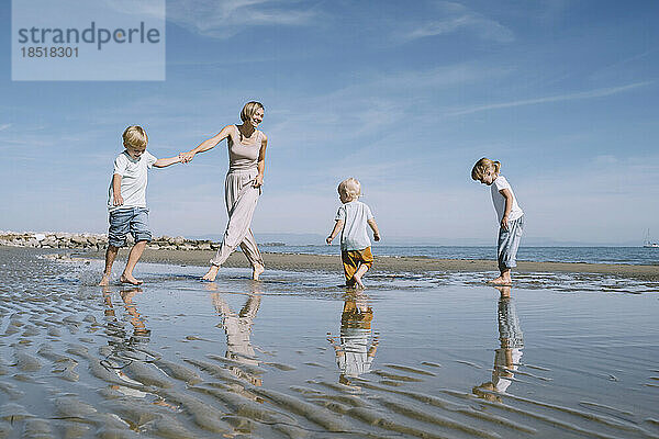 Glückliche Mutter  die mit Kindern am Strand spielt