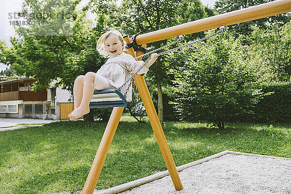 Happy girl swinging on swing at park