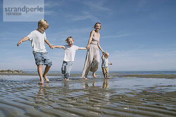 Glückliche Mutter hält Händchen mit Kindern und genießt den Strand