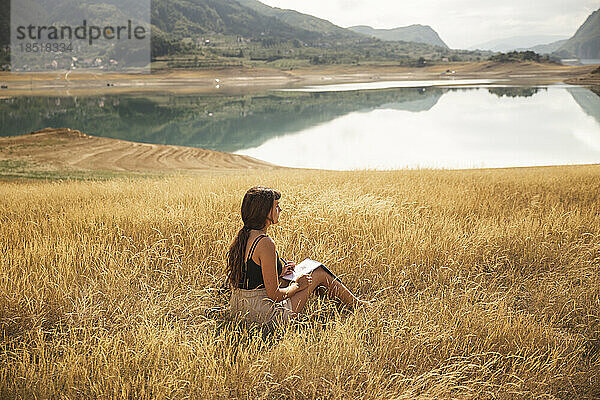 Junge Frau mit Skizzenblock sitzt vor dem Rama-See