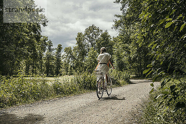 Frau fährt Fahrrad auf unbefestigter Straße