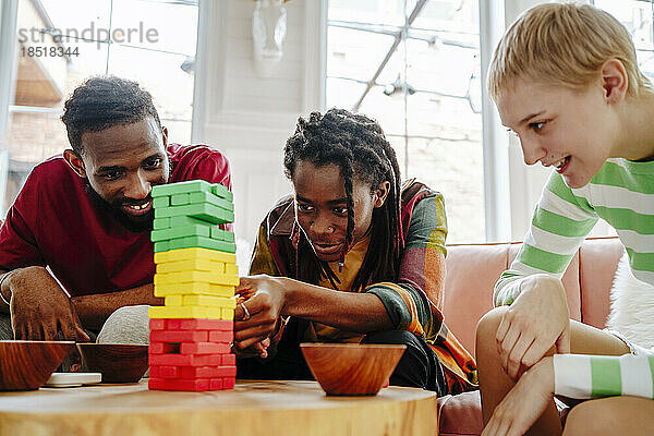 Lächelnder junger Mann  der mit Freunden ein Blockentfernungsspiel spielt