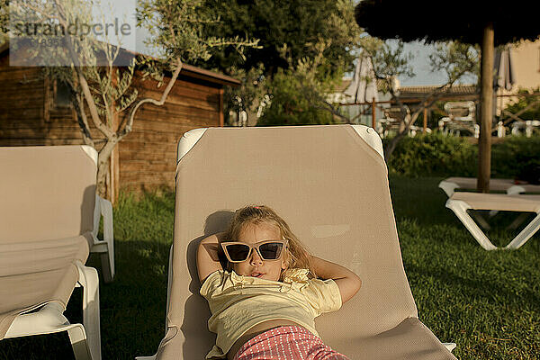 Girl wearing sunglasses lying on lounge chair