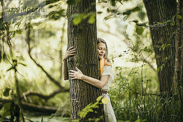 Woman embracing tree in forest