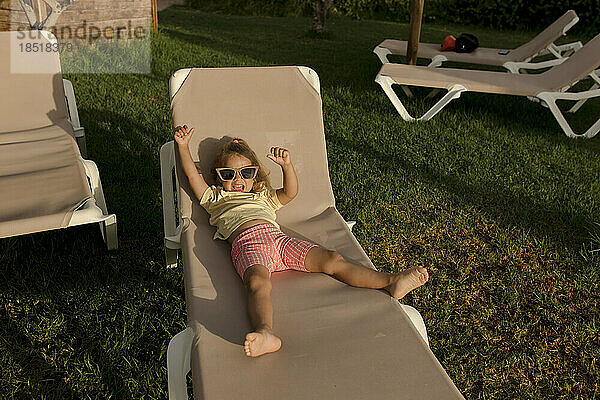 Fröhliches Mädchen  das sich auf einem Liegestuhl im Resort entspannt und genießt