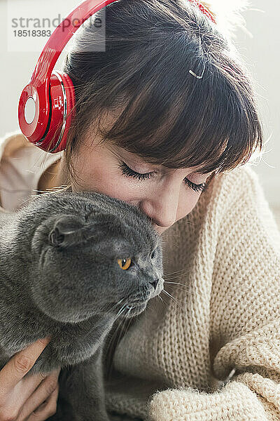 Frau mit kabellosen Kopfhörern verbringt ihre Freizeit mit Katze