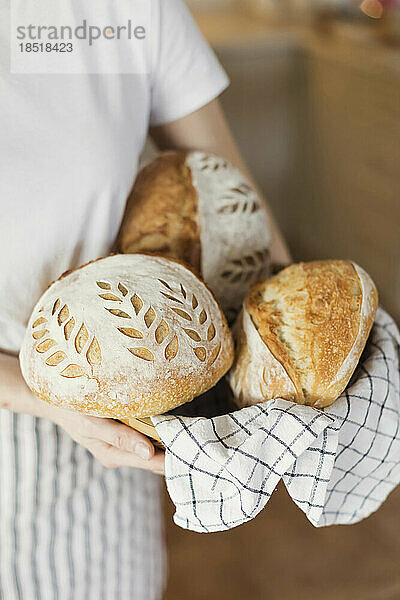 Frau hält frisch gebackenes Brot zu Hause