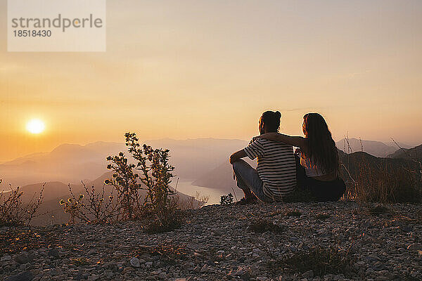 Paar sitzt und genießt den Sonnenuntergang
