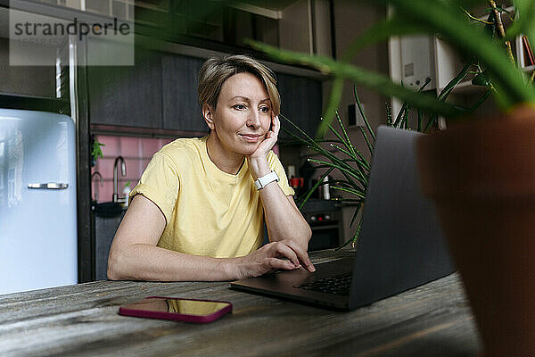 Reife Frau benutzt Laptop zu Hause