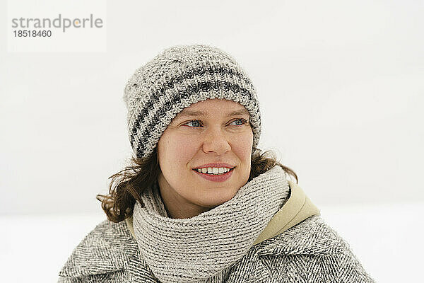 Nachdenklich lächelnde Frau mit Strickmütze im Winter
