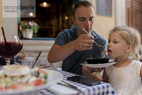 Mann füttert Tochter im Restaurant mit Garnelen