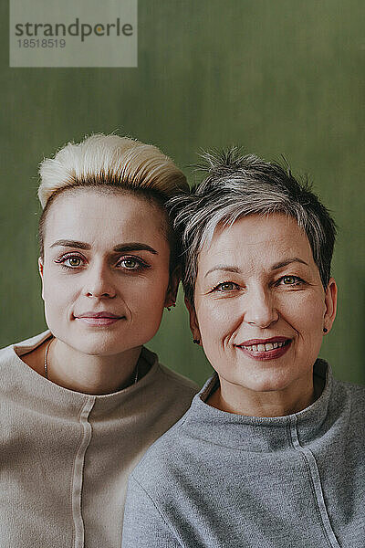 Mutter und Tochter mit kurzen Haaren vor grüner Wand
