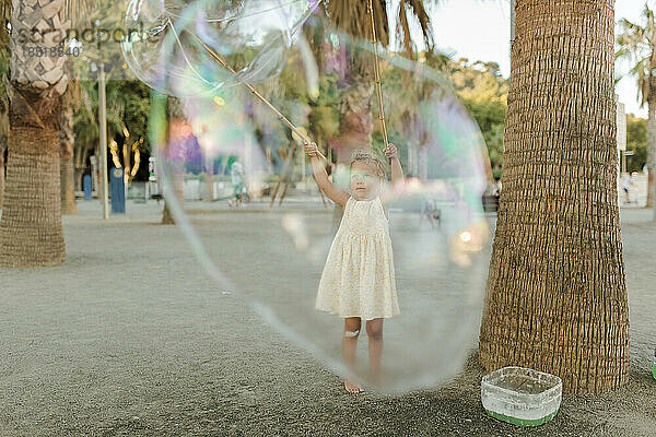 Mädchen spielt mit großer Seifenblase