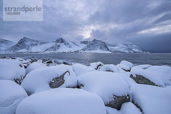 Norwegen  Troms und Finnmark  schneebedeckte Felsbrocken bei Tungenest Rasteplass mit Fjord und schneebedeckten Bergen im Hintergrund