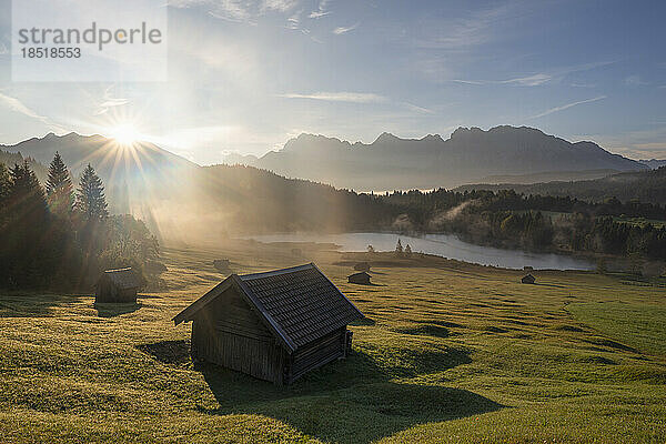 Deutschland  Bayern  abgeschiedene Hütten im Karwendelgebirge bei nebligem Sonnenaufgang mit dem Geroldsee im Hintergrund