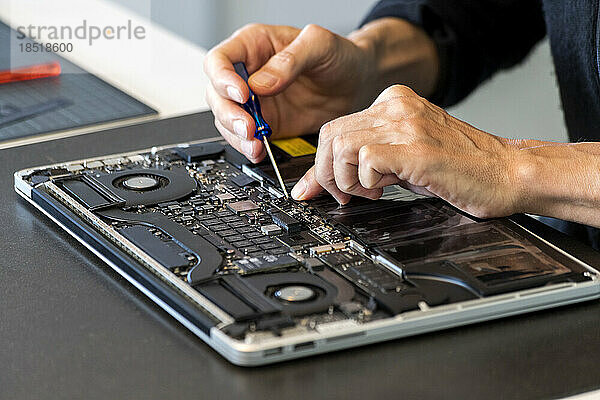 Mann repariert Laptop mit Schraubenzieher