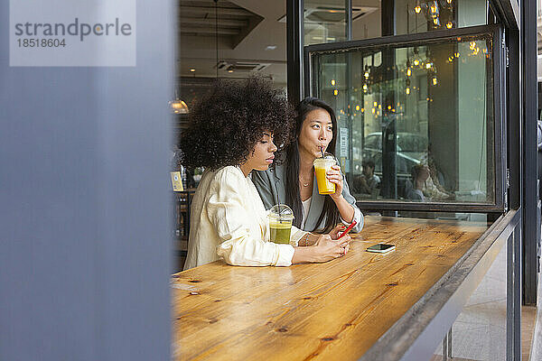 Frau benutzt Smartphone von Freund und trinkt Saft im Café