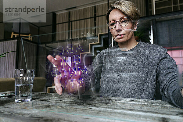 Frau mit Brille berührt zu Hause transparente Glasscheibe