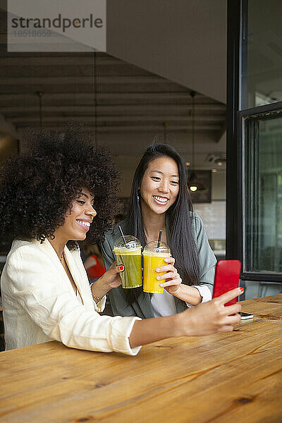 Freunde machen Selfie mit gesunden Getränken im Café
