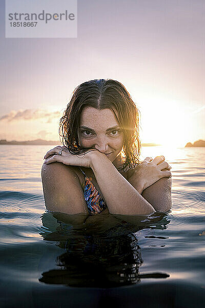 Junge Frau genießt den Sonnenuntergang im Meer