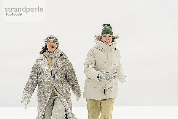 Glückliche Frau  die im Winter mit einer Freundin spaziert