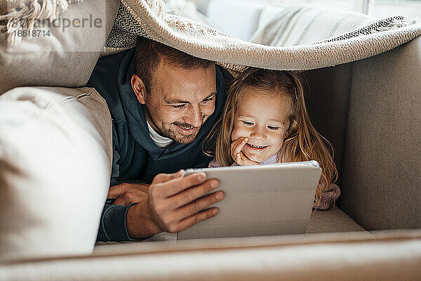 Glücklicher Vater und Tochter nutzen Tablet-PC unter der Decke zu Hause