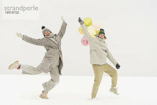 Fröhliche Freunde tanzen zusammen im Schnee