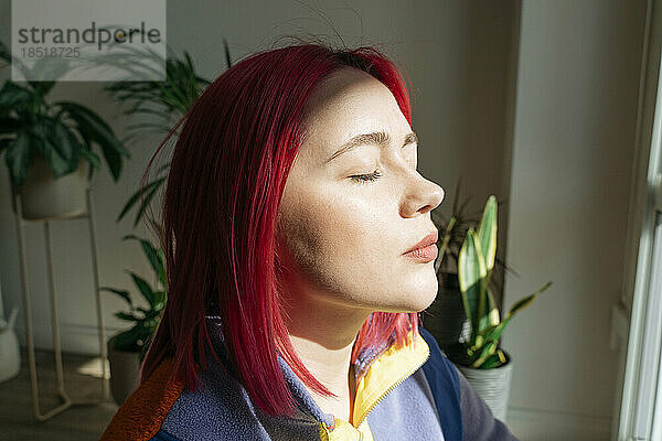 Frau mit geschlossenen Augen genießt Sonnenlicht im Gesicht
