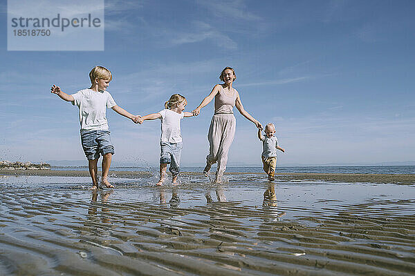 Glückliche Mutter  die mit Kindern am Strand genießt