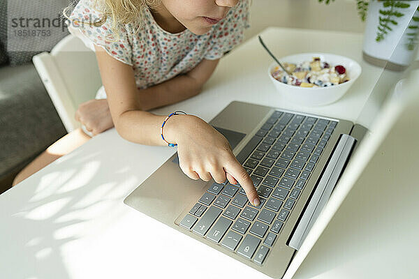 Mädchen tippt zu Hause auf der Laptop-Tastatur