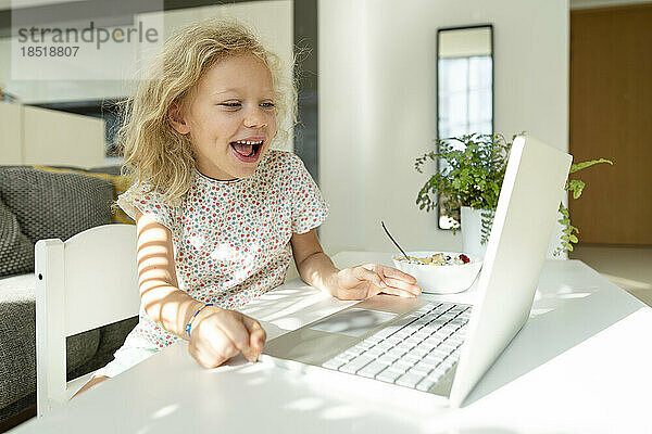 Fröhliches Mädchen  das es genießt  zu Hause einen Laptop zu benutzen
